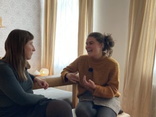 Zwei lachende Frauen sitzen am 